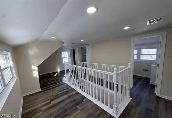 a view of a hallway with wooden floor and stairs