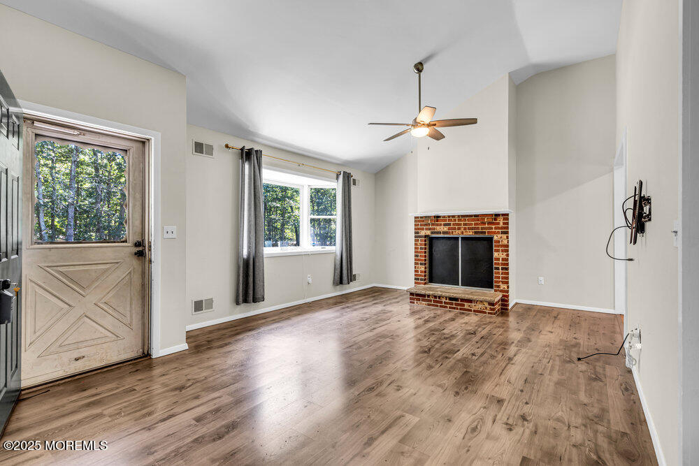 10 Bowman Road Jackson, NJ 08527 - Photo 4 of 16 an empty room with wooden floor fireplace and windows