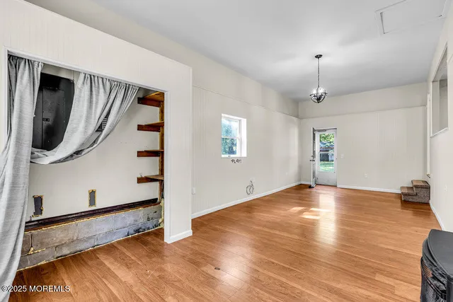 a view of an empty room with window and wooden floor