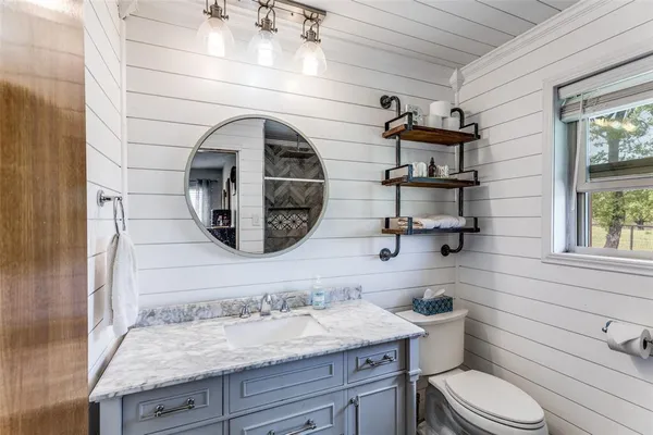 a bathroom with a granite countertop toilet sink and mirror