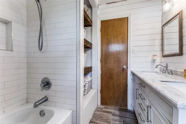 a bathroom with a granite countertop bathtub shower sink and mirror