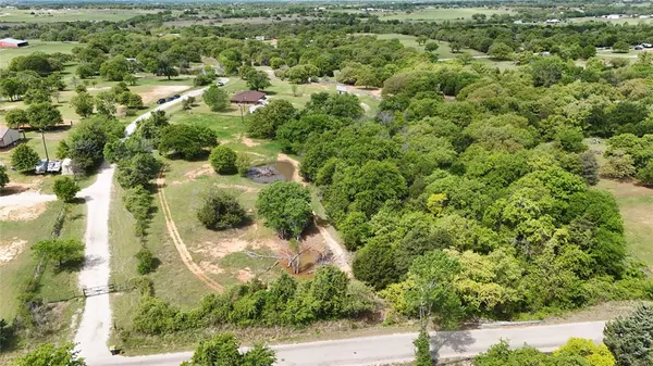 an aerial view of residential houses with outdoor space and trees
