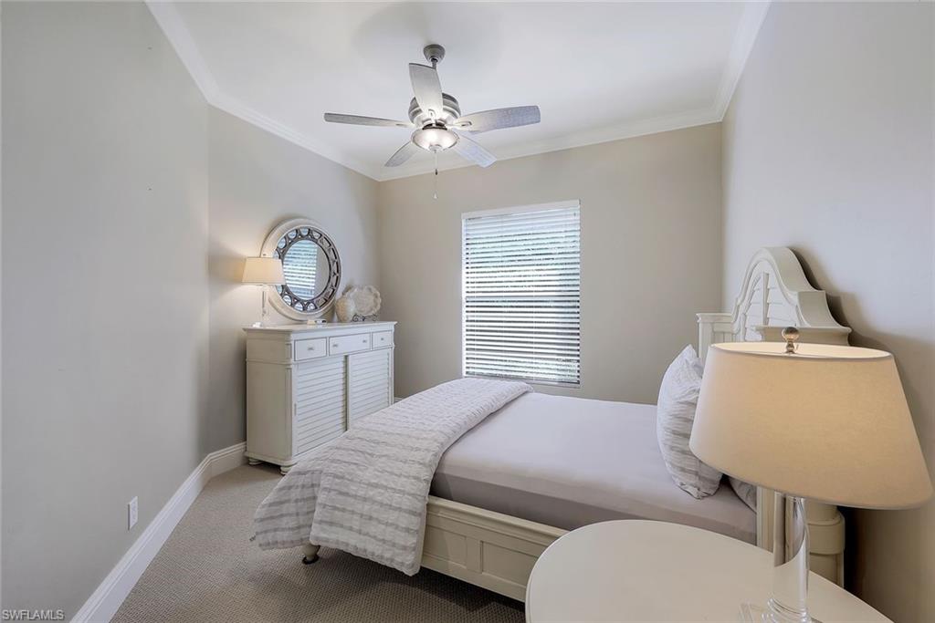 7598 Moorgate Point Way Naples, FL 34113 - Photo 18 of 33 a bedroom with a bed a mirror on dresser and a window