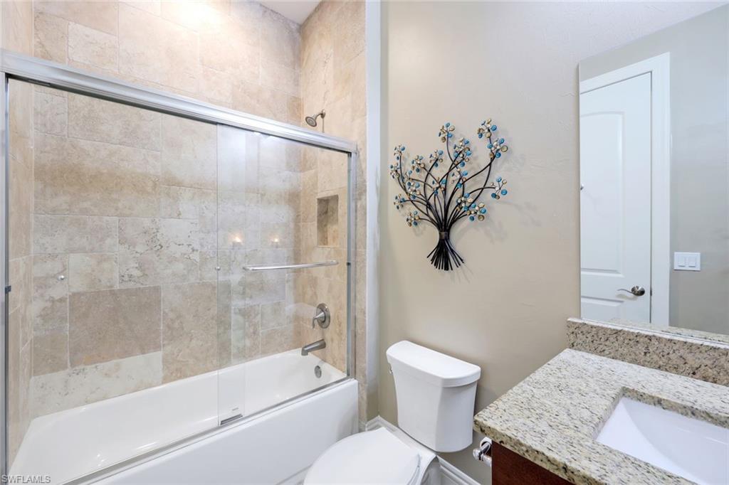 7598 Moorgate Point Way Naples, FL 34113 - Photo 19 of 33 a bathroom with a granite countertop bathtub shower sink vanity and toilet