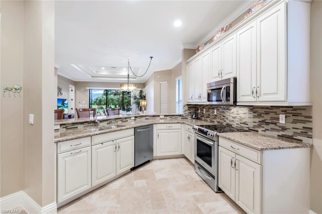 7598 Moorgate Point Way Naples, FL 34113 - Photo 7 of 33 a kitchen with white cabinets stainless steel appliances and sink
