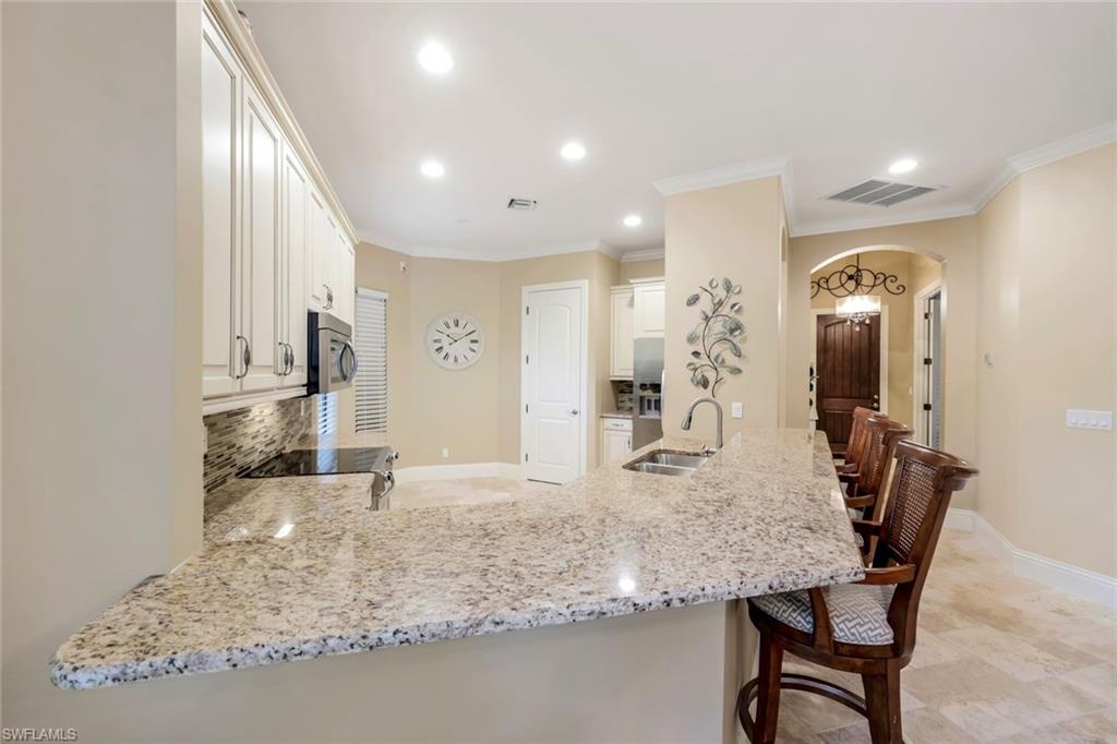 7598 Moorgate Point Way Naples, FL 34113 - Photo 9 of 33 a view of a kitchen with kitchen island granite countertop wooden floor and a refrigerator