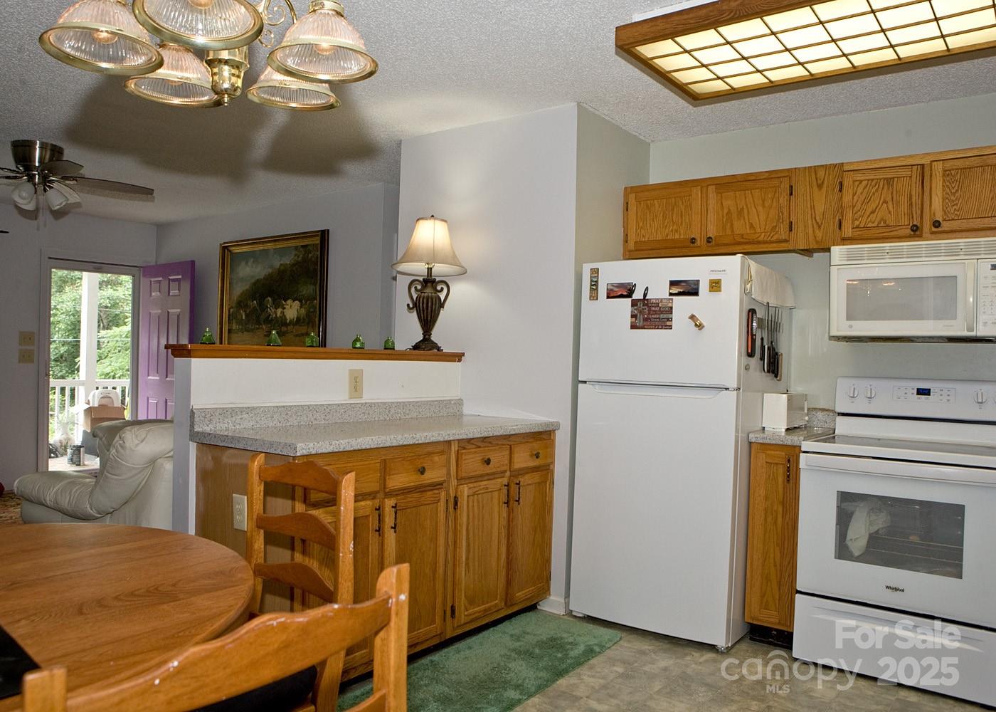 165 Peepeye Cove Road Leicester, NC 28748 - Photo 11 of 24 a kitchen with a table chairs refrigerator and cabinets