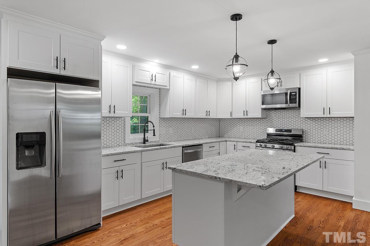 2609 Elmhurst Circle Raleigh, NC 27610 - Photo 10 of 34 a kitchen with stainless steel appliances granite countertop a sink a stove a refrigerator and island with wooden floor