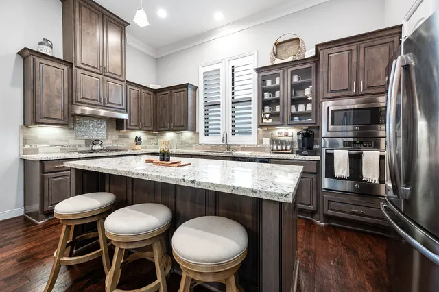 a kitchen with stainless steel appliances a table chairs refrigerator and sink