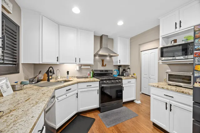 a kitchen with stainless steel appliances granite countertop a stove top oven a sink dishwasher and a refrigerator with wooden cabinets