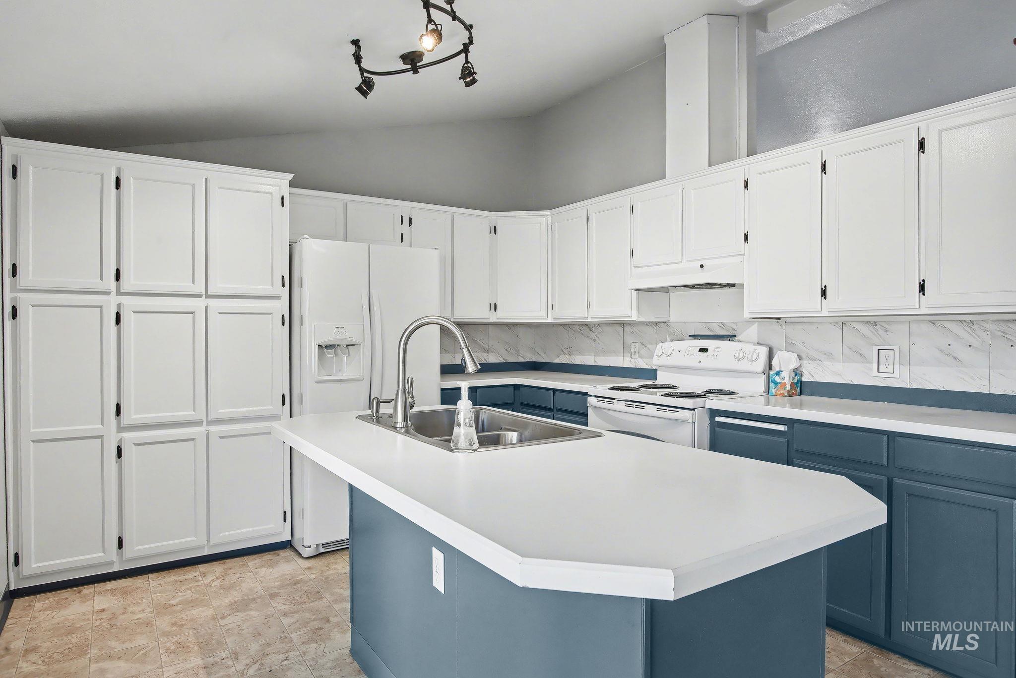 1430 Chestnut Street, Unit 28 Clarkston, WA 99403 - Photo 5 of 34 Kitchen featuring white cabinetry, white appliances, light countertops, a kitchen island with sink, and vaulted ceiling