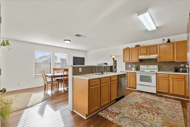 a kitchen with a stove sink cabinets and wooden floor