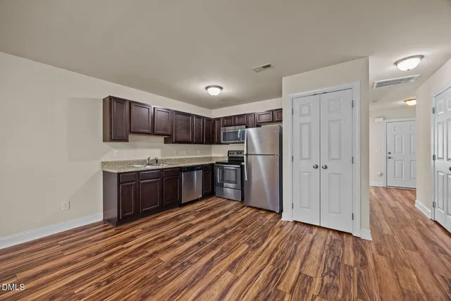 a kitchen with wooden floors stainless steel appliances a sink and cabinets