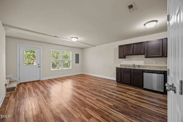 a view of an empty room with wooden floor and a window
