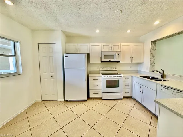 a kitchen with white cabinets and white appliances