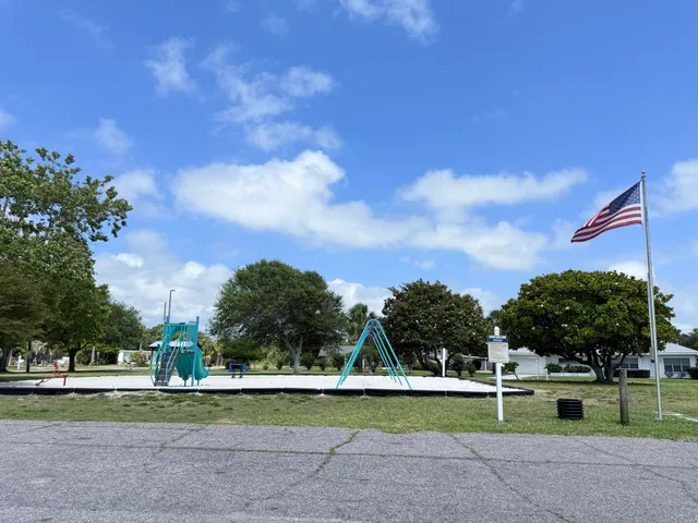 a view of a big yard with table and trees in the background