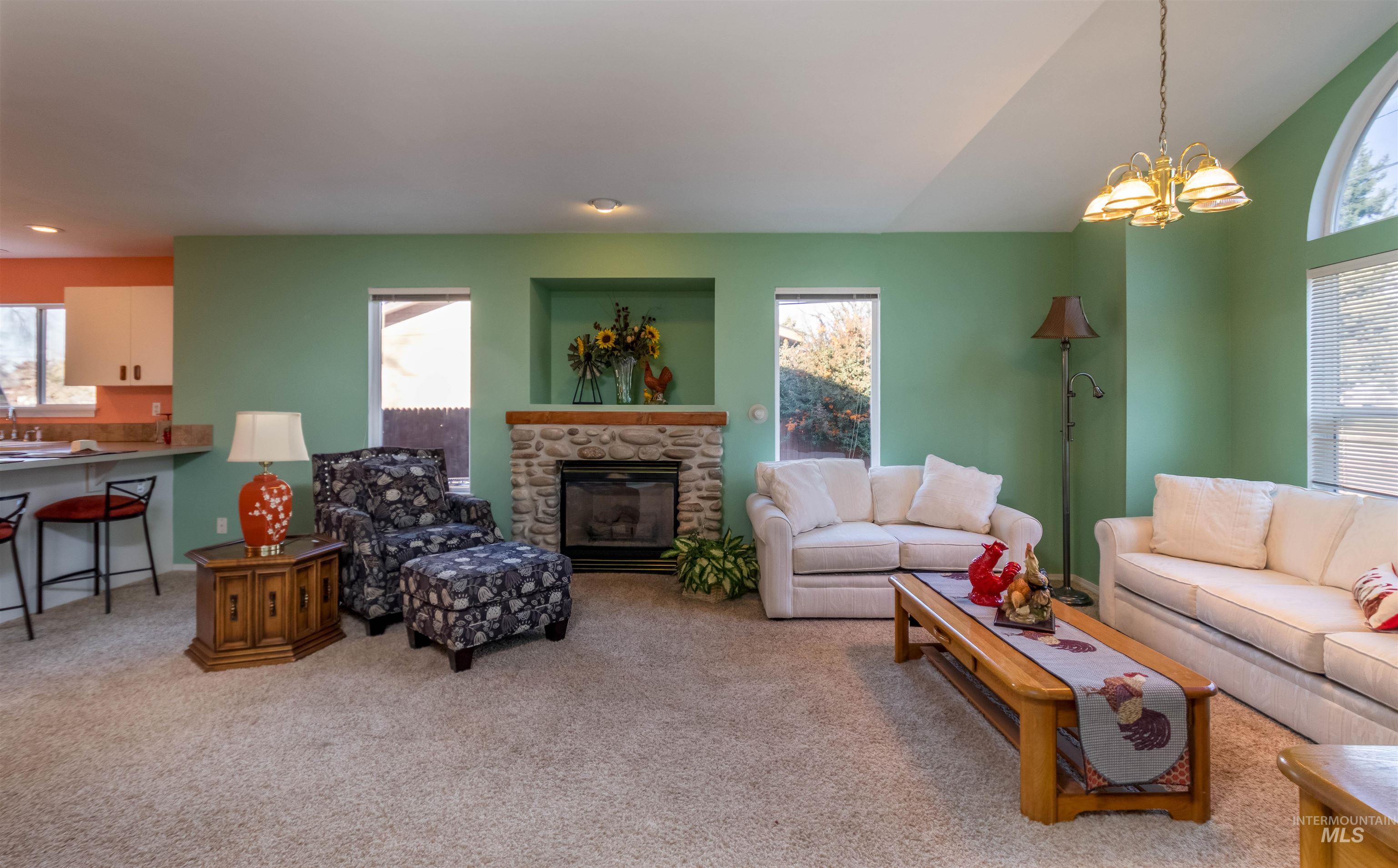1811 Cleveland Street Boise, ID 83705 - Photo 4 of 30 Living area with light carpet, a chandelier, a stone fireplace, and vaulted ceiling