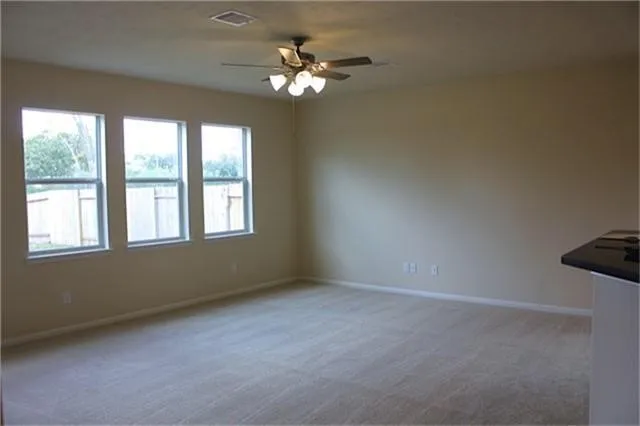 an empty room with windows and fan