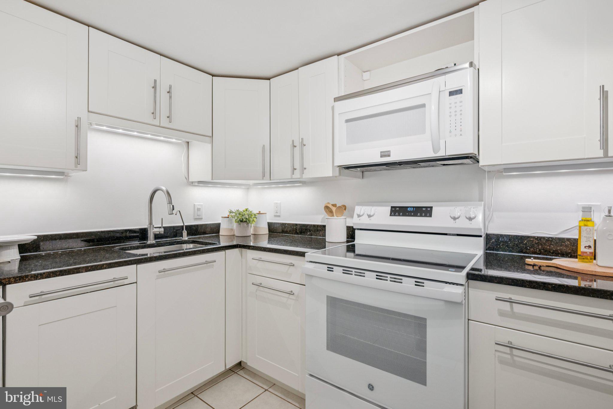 2630 Adams Mill Road Northwest, Unit 103 Washington, DC 20009 - Photo 7 of 24 a kitchen with white cabinets and white appliances