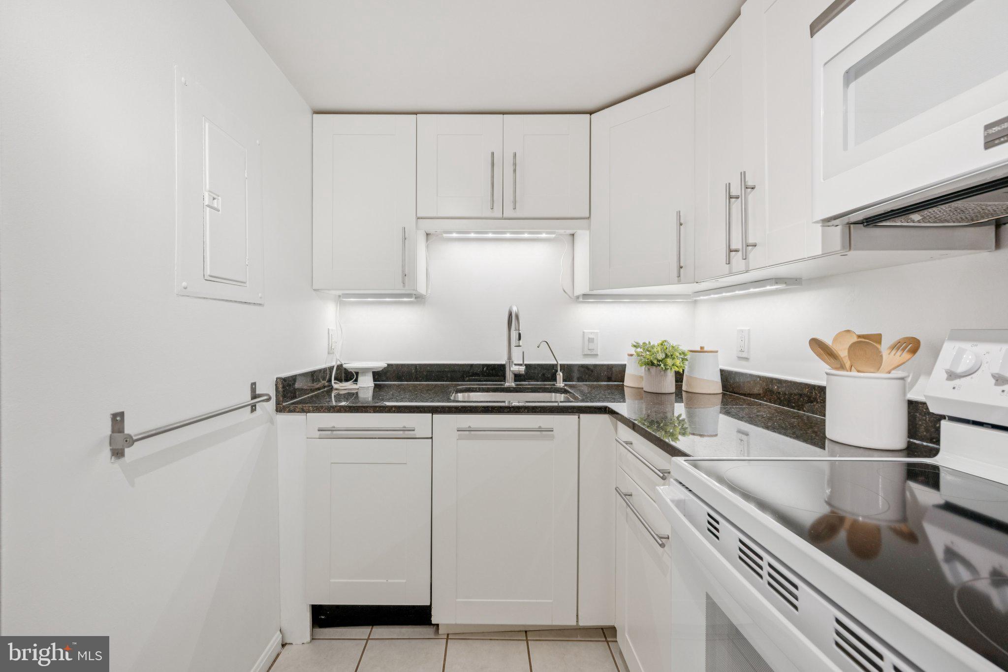 2630 Adams Mill Road Northwest, Unit 103 Washington, DC 20009 - Photo 8 of 24 a white kitchen with stainless steel appliances granite countertop a sink and cabinets