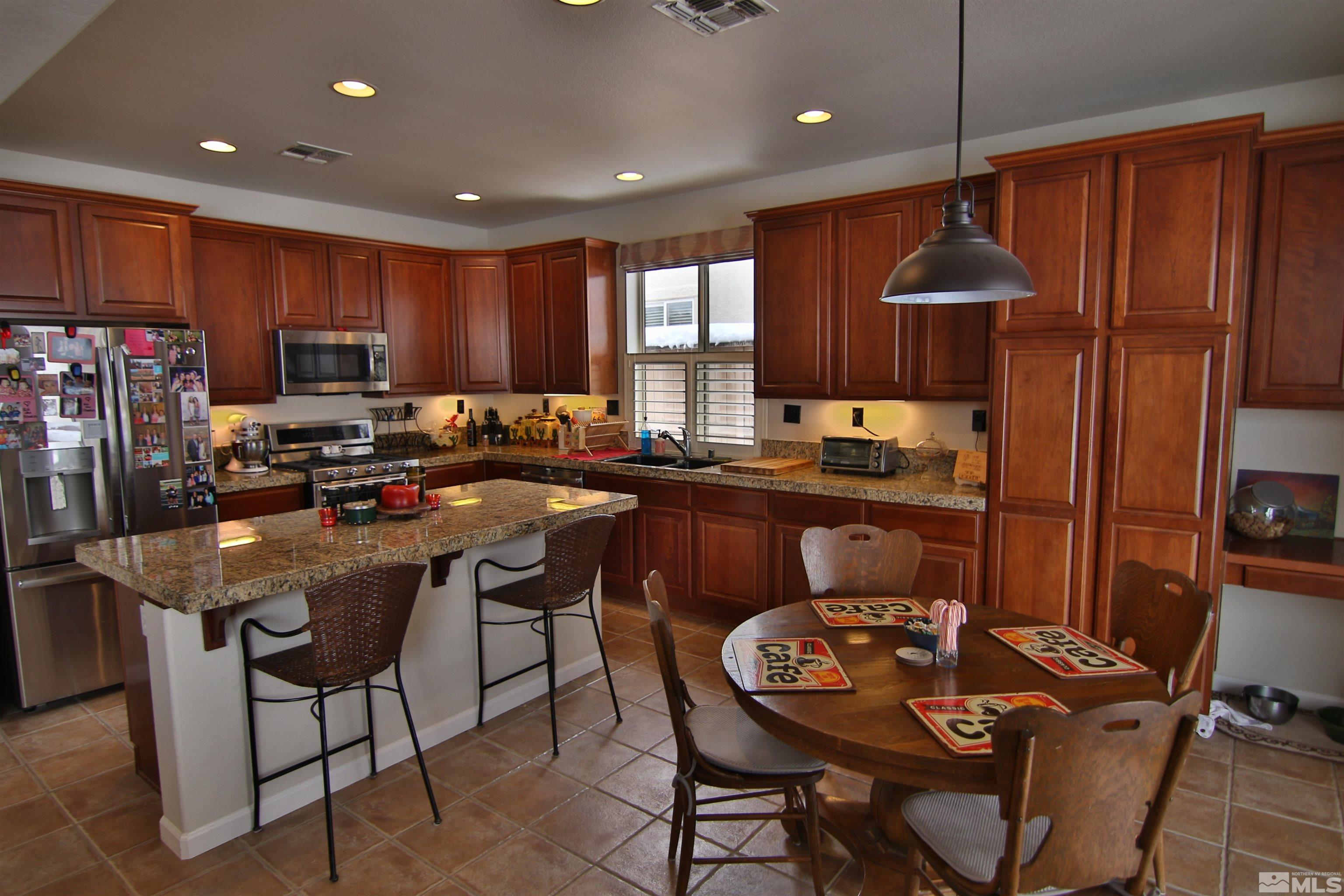 10640 Fire Poppy Circle Reno, NV 89521 - Photo 2 of 27 a kitchen with granite countertop a refrigerator a stove a sink a dining table and chairs with wooden floor