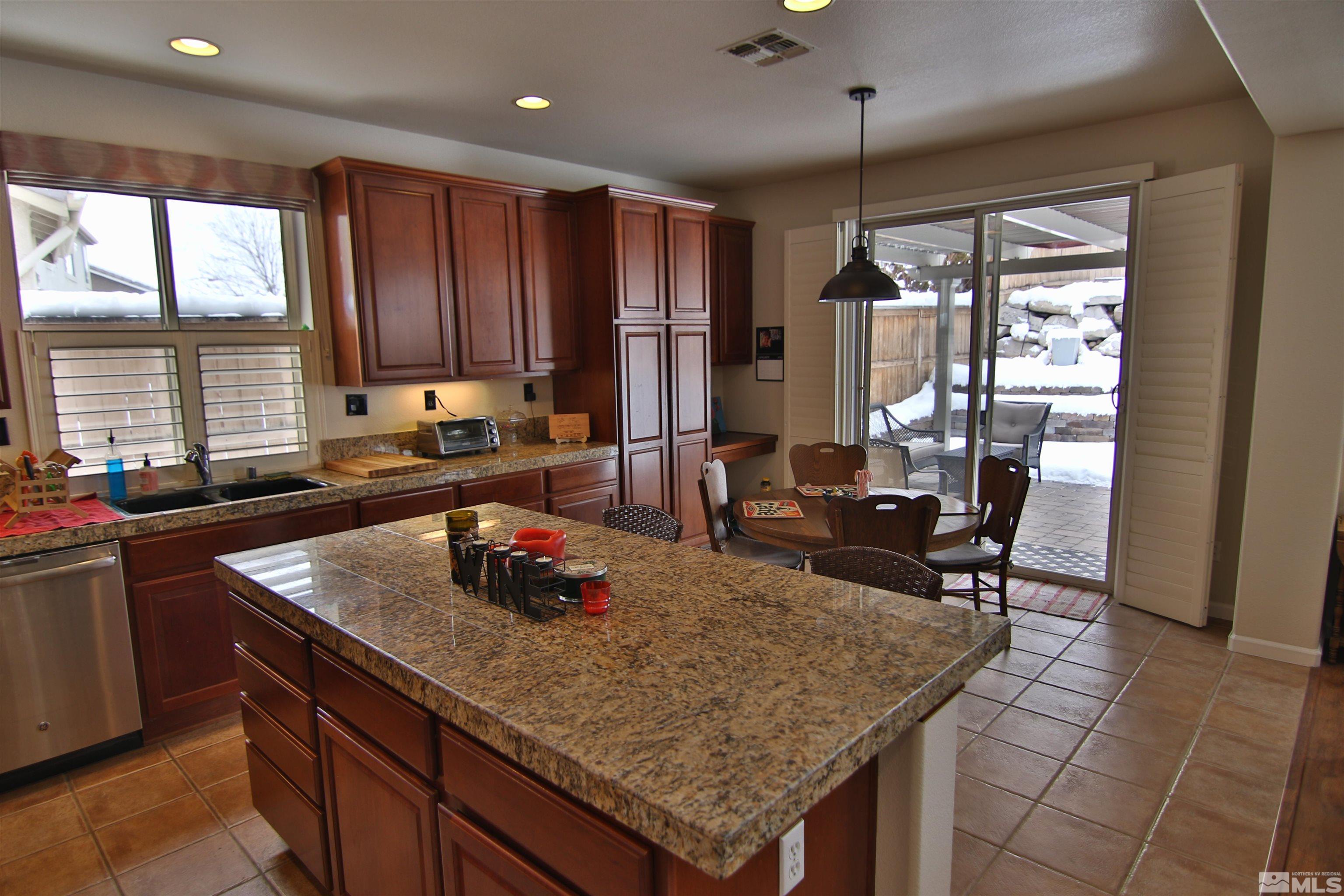 10640 Fire Poppy Circle Reno, NV 89521 - Photo 7 of 27 a kitchen with a stove a refrigerator a sink dishwasher with a dining table and chair with wooden floor