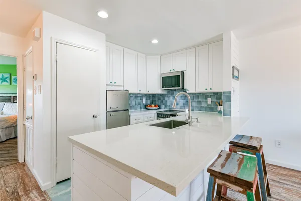 a kitchen with kitchen island a stove a sink a microwave a refrigerator and cabinets