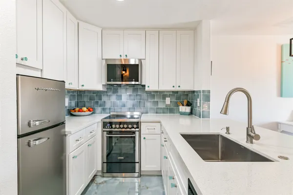a kitchen with white cabinets and stainless steel appliances