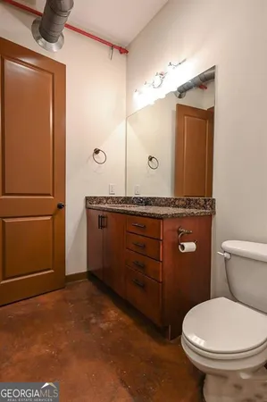 a bathroom with a granite countertop toilet sink and mirror