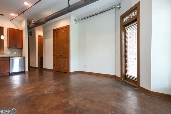a view of an empty room with a window and wooden floor