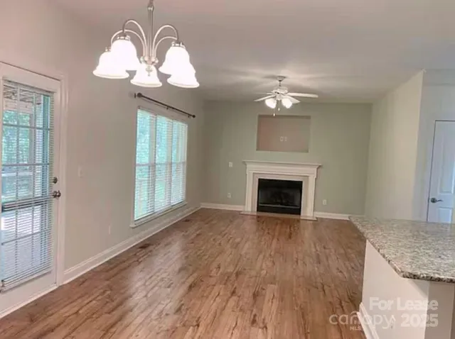 a view of a livingroom with a chandelier fan a fireplace and wooden floor