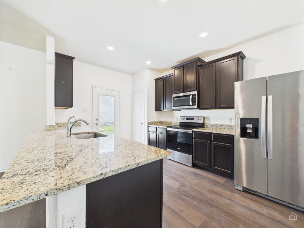 1687 Twin Estates Drive Kyle, TX 78640 - Photo 1 of 1 a kitchen with kitchen island granite countertop stainless steel appliances and wooden cabinets