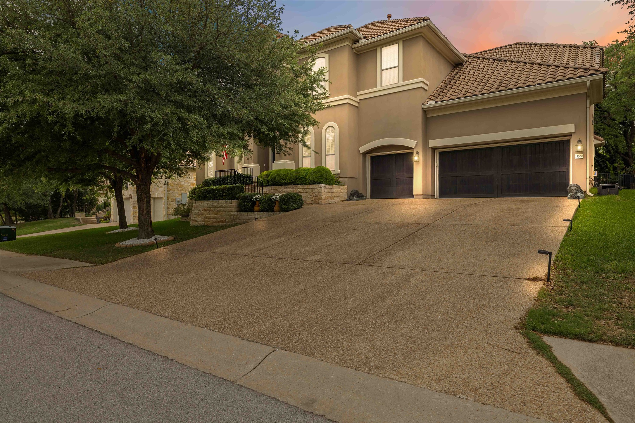 The property features a stucco exterior, a tiled roof, and an expansive driveway
