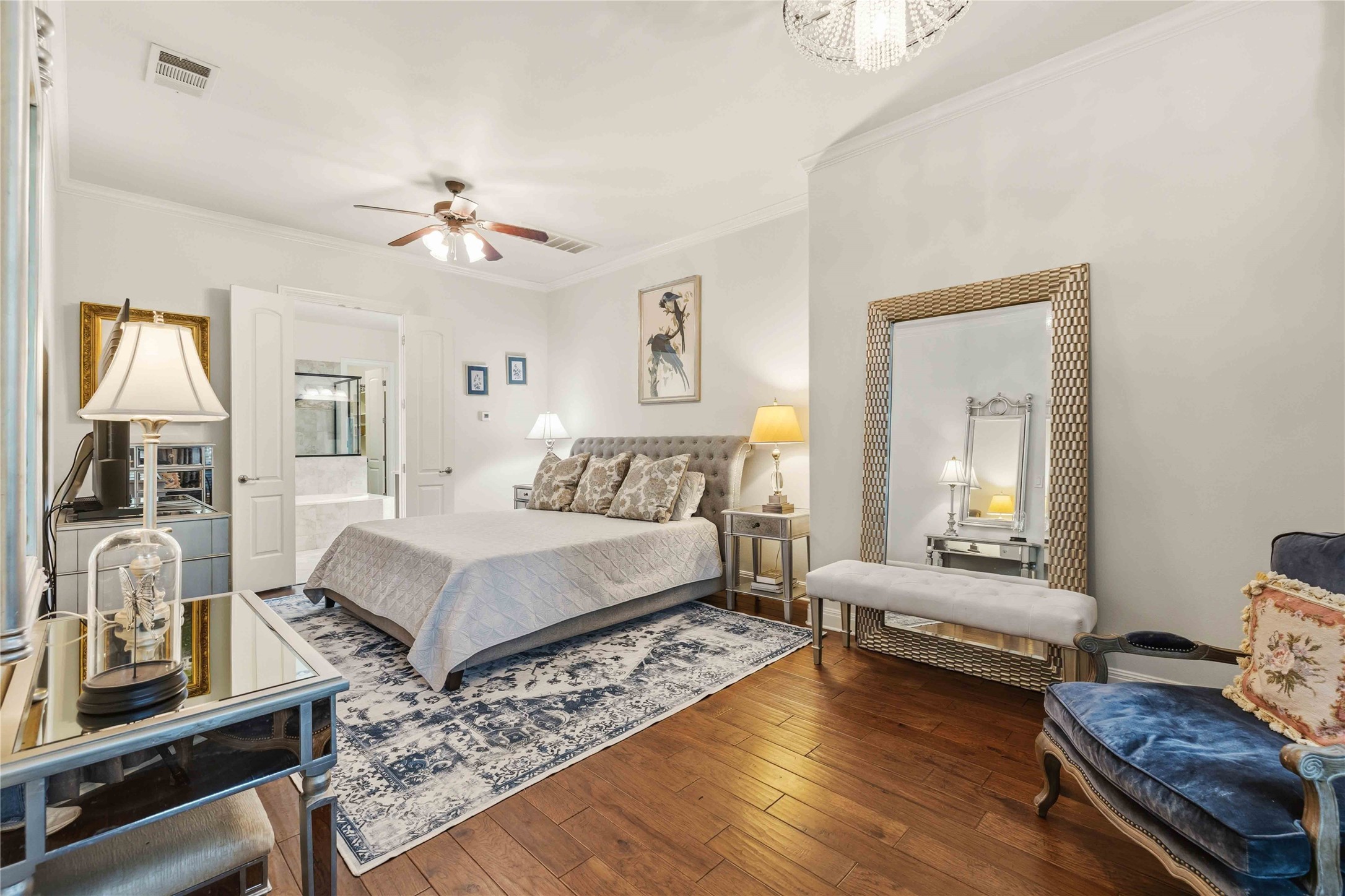 15200 Spillman Ranch Loop Austin, TX 78738 - Photo 16 of 40 Primary Bedroom featuring hardwood flooring, a ceiling fan, and double doors leading to a bathroom with a white tub