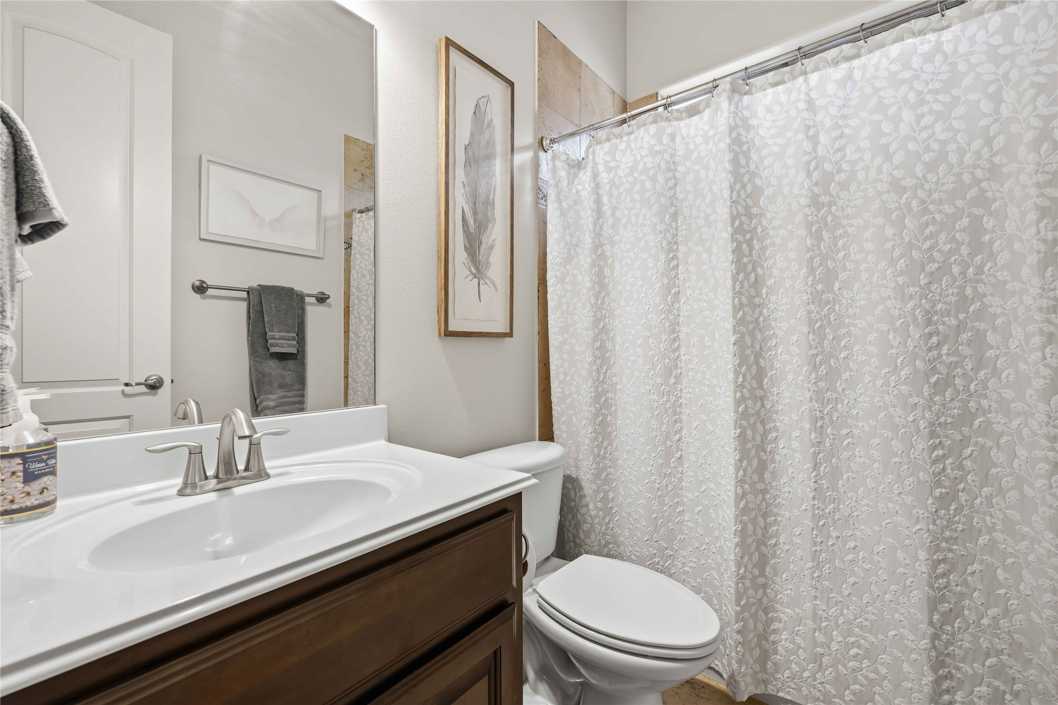 15200 Spillman Ranch Loop Austin, TX 78738 - Photo 22 of 40 Bathroom featuring a vanity with a white countertop and an undermount sink, a toilet, and a shower with a patterned white shower curtain