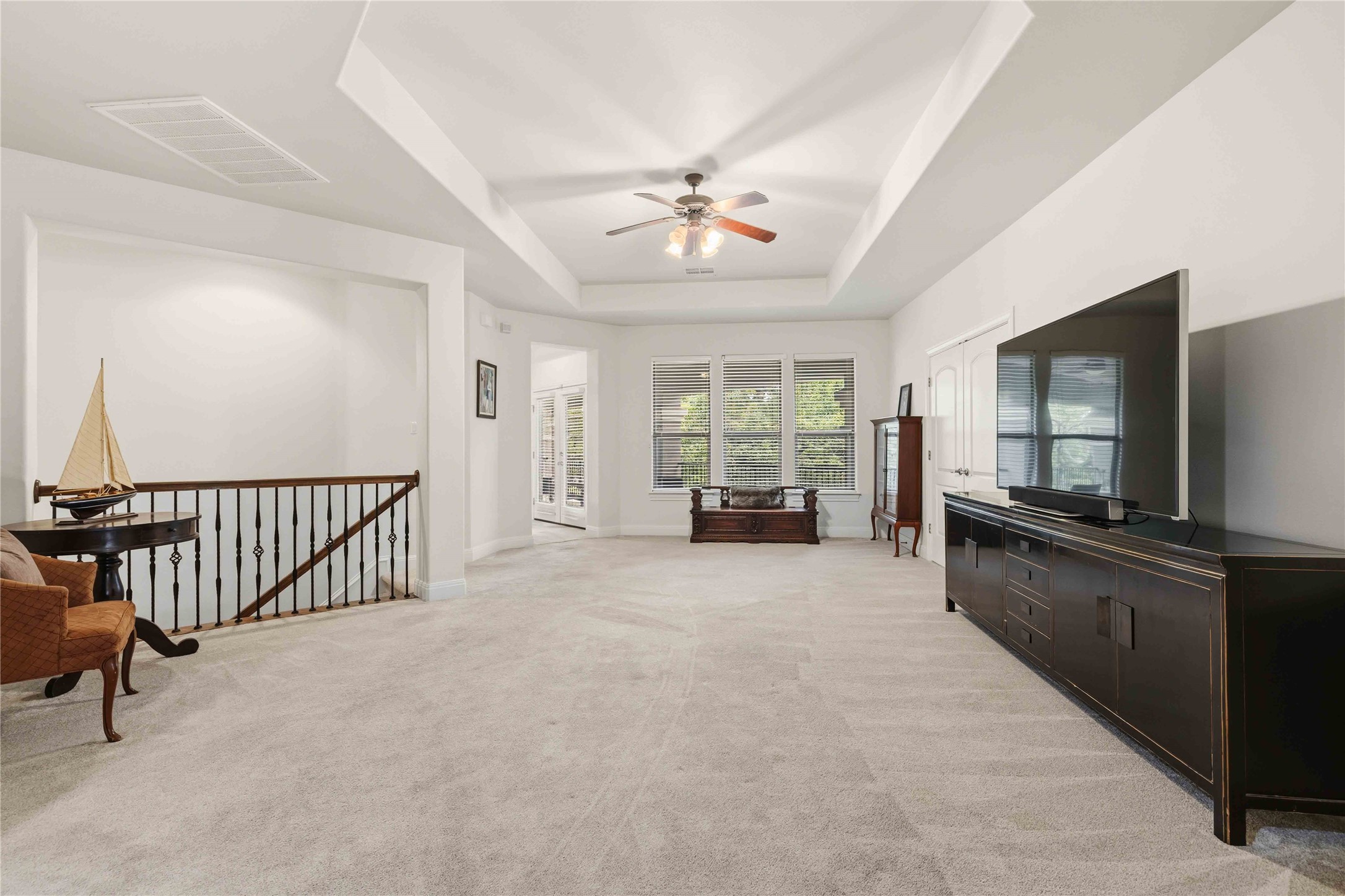 15200 Spillman Ranch Loop Austin, TX 78738 - Photo 25 of 40 Expansive carpeted living area/gameroom upstairs featuring a tray ceiling with a ceiling fan, white walls, and a view of windows