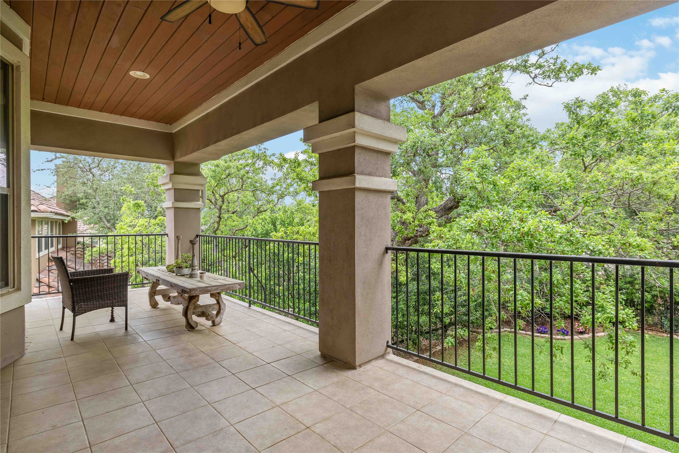 15200 Spillman Ranch Loop Austin, TX 78738 - Photo 32 of 40 The property features a spacious outdoor patio with tiled flooring and a wood paneled ceiling, offering a verdant view of mature trees and a grassy area