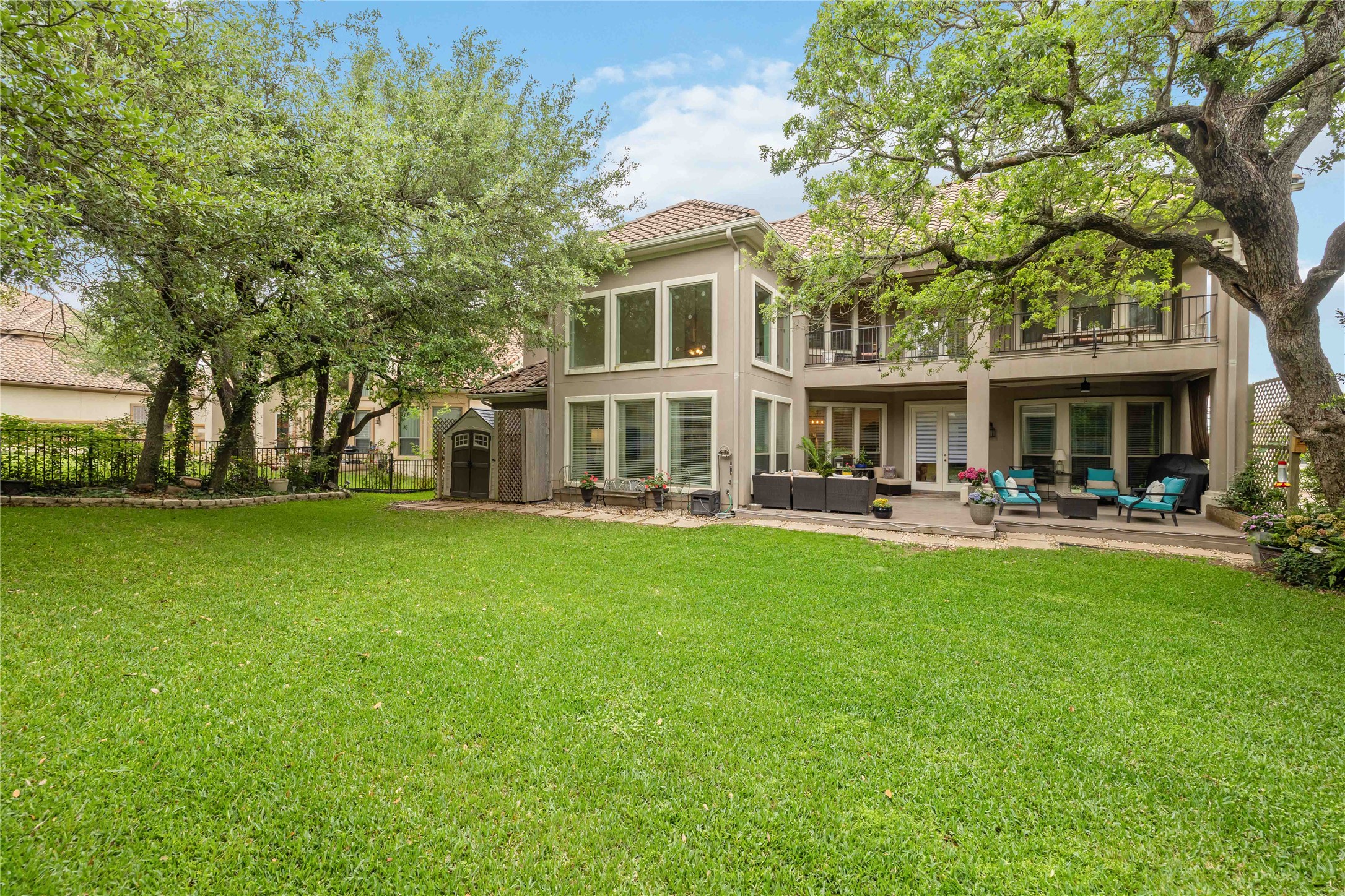 15200 Spillman Ranch Loop Austin, TX 78738 - Photo 37 of 40 The property features a spacious lawn with mature trees, a ground-level patio, and a second-story balcony