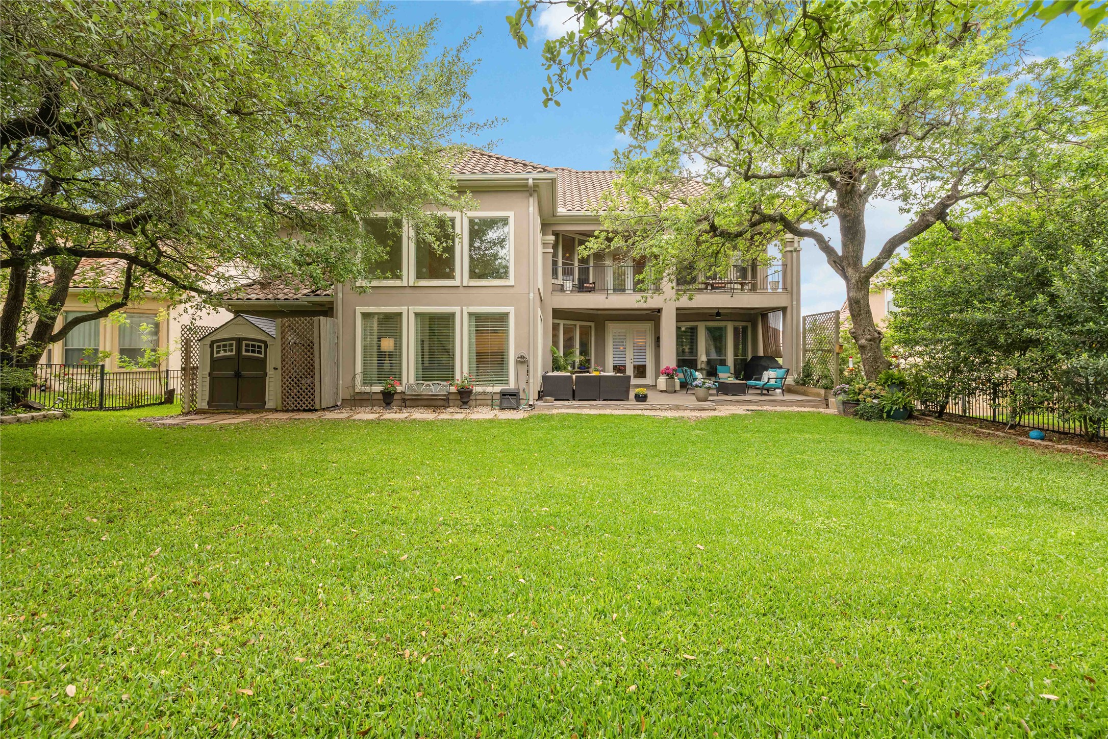 15200 Spillman Ranch Loop Austin, TX 78738 - Photo 39 of 40 The property features a spacious backyard with a large lawn, mature trees, and a patio area