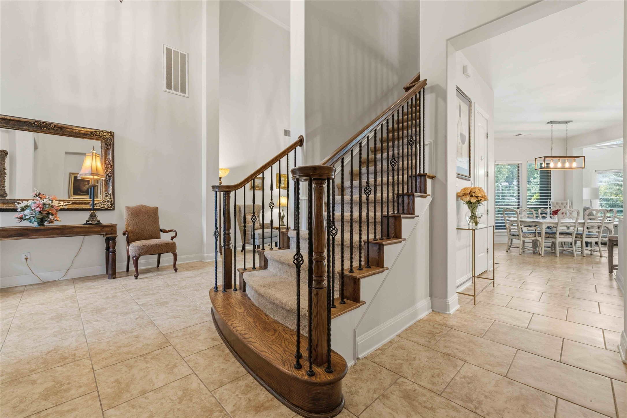 15200 Spillman Ranch Loop Austin, TX 78738 - Photo 6 of 40 This entryway features a grand staircase with wooden handrails and decorative wrought iron balusters, complemented by light-colored tile flooring