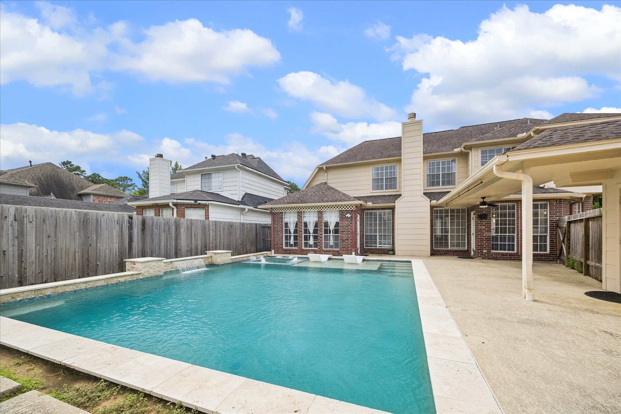 7915 Huddersfield Court Spring, TX 77379 - Photo 9 of 37 The backyard offers a true outdoor retreat with a large pool, sun deck, water features, patio space, and a detached 3-car garage just beyond the covered breezeway.