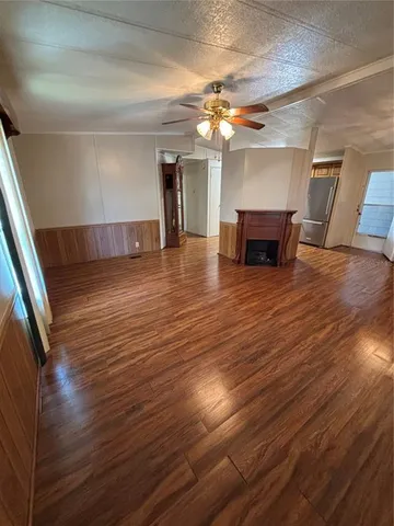 a view of an empty room with wooden floor and a ceiling fan