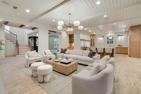 a living room with furniture kitchen view and a chandelier