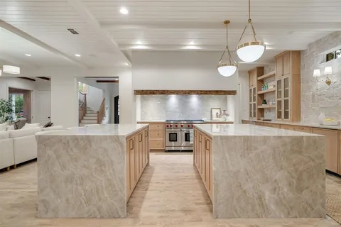 a large kitchen with kitchen island a large counter space a sink and stainless steel appliances