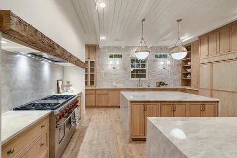 a kitchen with stainless steel appliances granite countertop a sink a stove and a wooden floors