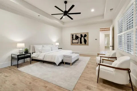 a spacious bedroom with a bed a couch and a ceiling fan