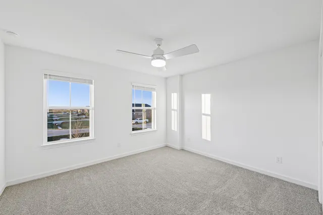 an empty room with windows and ceiling fan