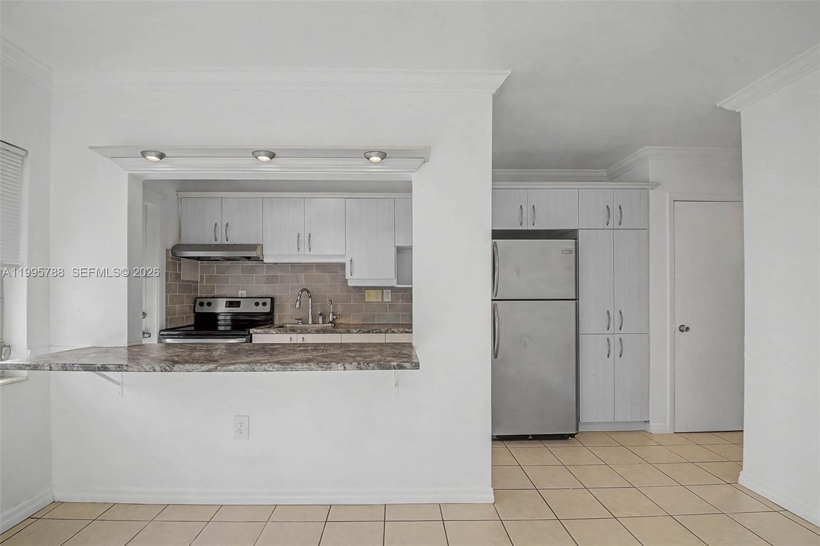 60 Northwest 79th Street, Unit 23 Miami, FL 33150 - Photo 1 of 23 a kitchen with kitchen island white cabinets and refrigerator