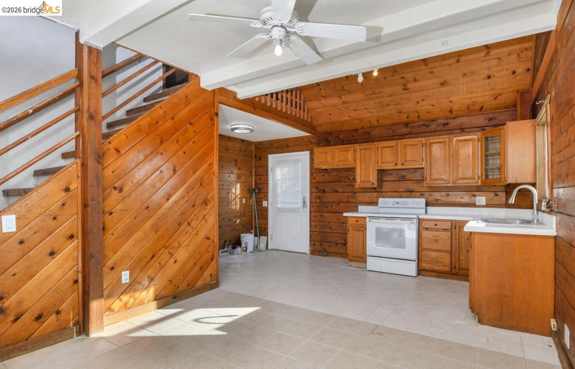 5980 Piper Road Bethel Island, CA 94511 - Photo 17 of 24 Kitchen featuring wooden walls, light countertops, white electric range oven, brown cabinetry, and glass insert cabinets