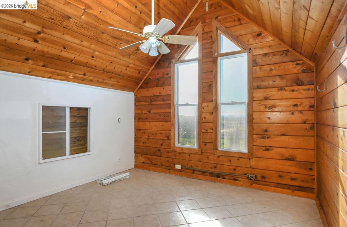 5980 Piper Road Bethel Island, CA 94511 - Photo 9 of 24 Empty room featuring wood ceiling, plenty of natural light, wooden walls, vaulted ceiling, and ceiling fan